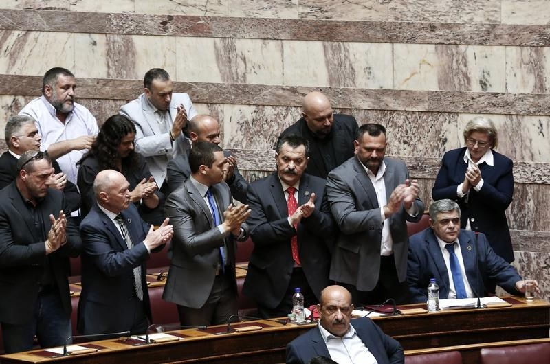 © Reuters. Lawmakers of far-right Golden Dawn party applaud after the speech of their leader Nikos Michaloliakos during  a parliament session  in Athens