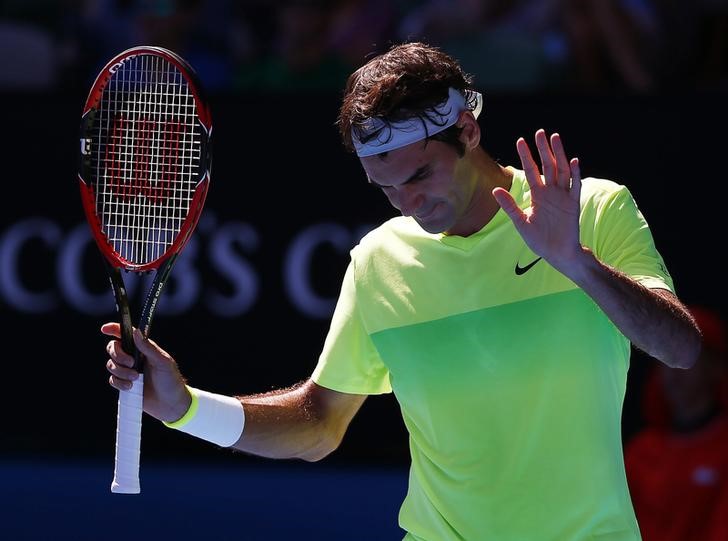© Reuters. Federer of Switzerland gestures to Seppi of Italy after hitting the net-cord during their men's singles third round match at the Australian Open 2015 tennis tournament in Melbourne