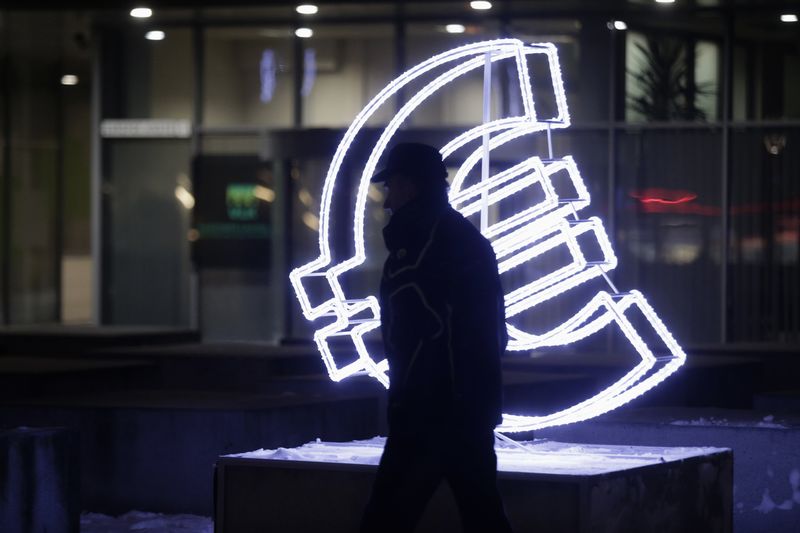 © Reuters. A man walks past an Euro sign light installation in Vilnius