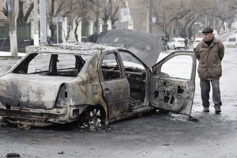 © Reuters. Мужчина смотрит на сгоревший автомобиль в Донецке