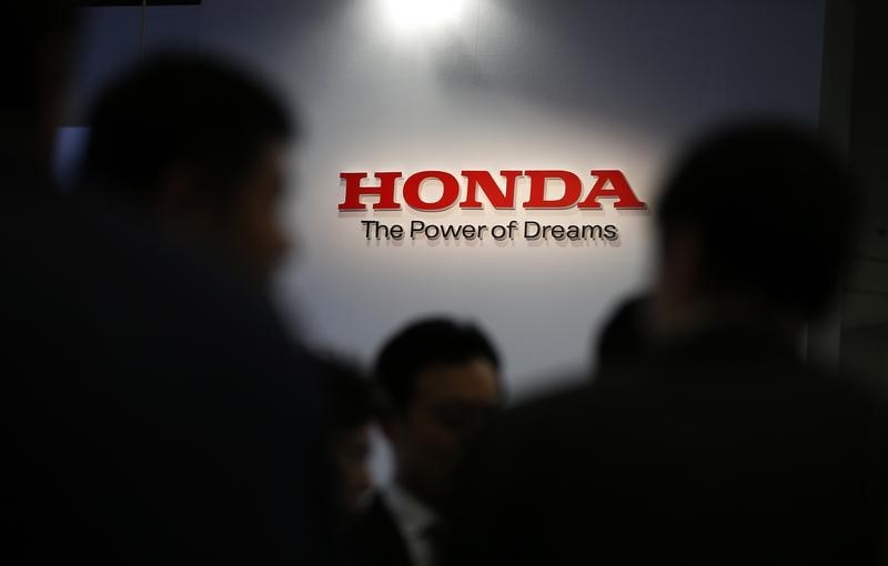 © Reuters. A logo of Honda Motor Co is seen behind journalists after the unveiling event for the company's all-new hybrid sedan "Grace" in Tokyo