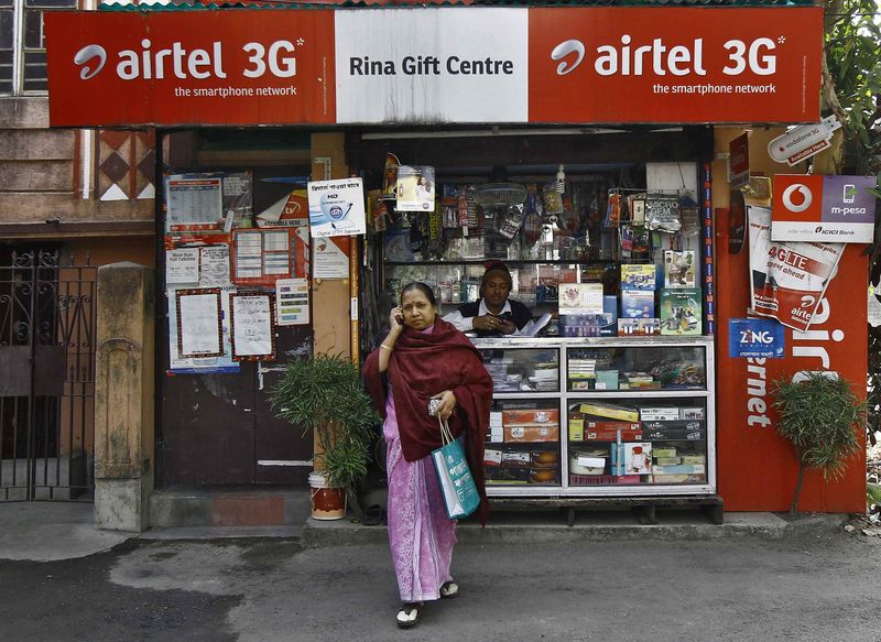 © Reuters. A woman speaks on her mobile phone after recharging it at a local stationary cum prepaid mobile recharge shop in Kolkata