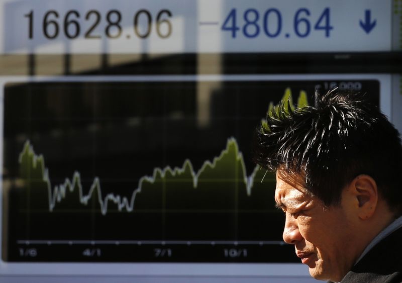 © Reuters. Man walks past an electronic board showing Japan's Nikkei average, outside a brokerage in Tokyo