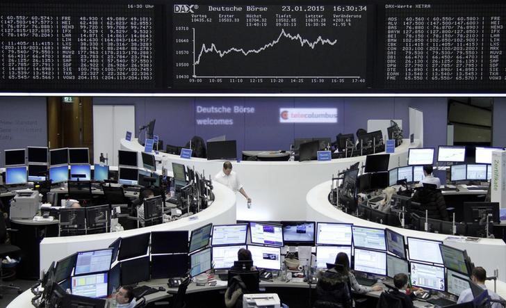 © Reuters. Traders work at their screens in front of the German share price index DAX board at the stock exchange in Frankfurt