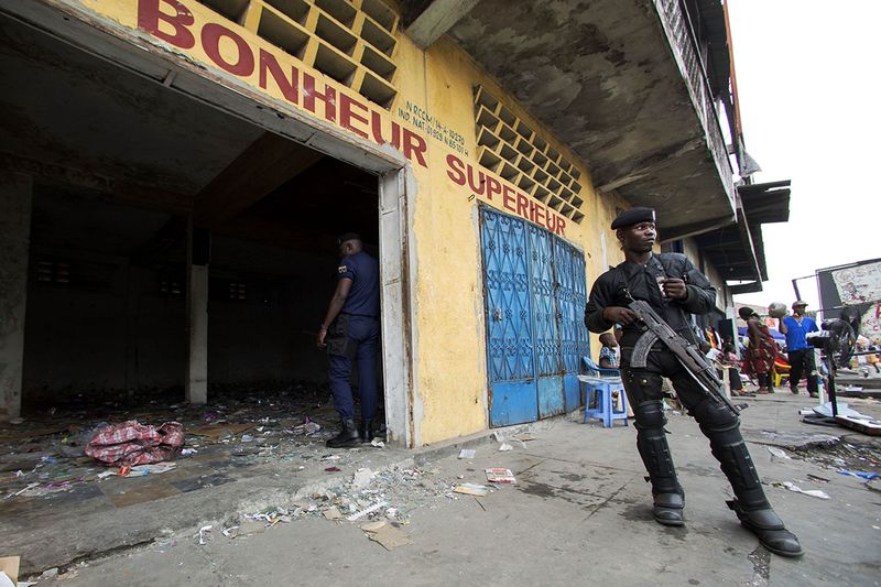 © Reuters. A police officer stands guard in front of a store that was looted during violent protests in Kinshasa