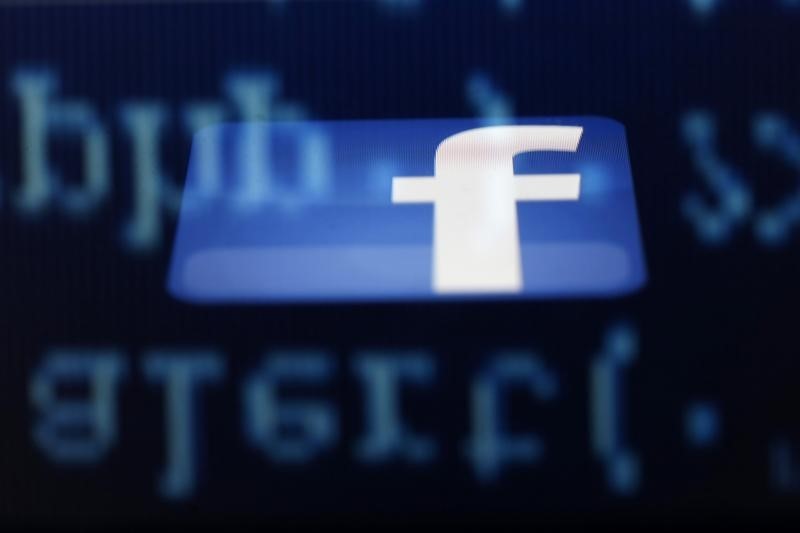 © Reuters. A Facebook logo on an Ipad is reflected among source code on the LCD screen of a computer in this photo illustration