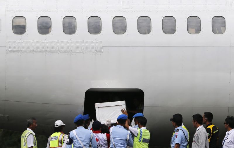 © Reuters. Indonesia soldiers and rescue personnel put a coffin of a passenger of AirAsia Flight QZ8501 into the cargo compartment of a Trigana airplane at Iskandar airbase in Pangkalan Bun