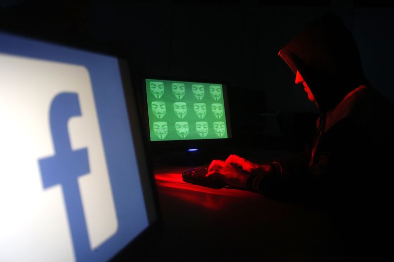 © Reuters. Un ragazzo lavora al suo pc, a fianco il logo di Facebook 