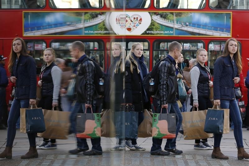 © Reuters. Shoppers are reflected in a window as they carry bags along Oxford street during the final weekend of shopping before Christmas in London