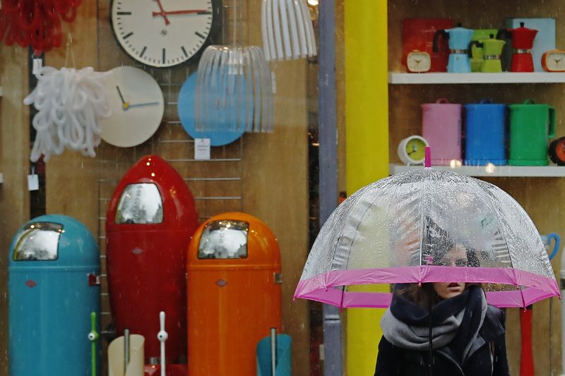 © Reuters. A woman carrying an umbrella passes a shop selling household goods, in Brighton