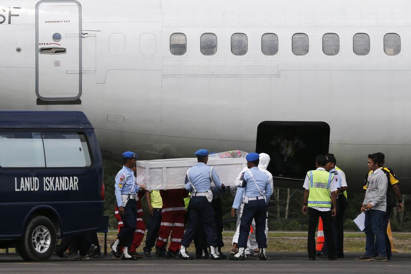 © Reuters. Indonesia soldiers and rescue personnel prepare to put a coffin of a passenger of AirAsia Flight QZ8501 into the cargo compartment of a Trigana airplane at Iskandar airbase in Pangkalan Bun