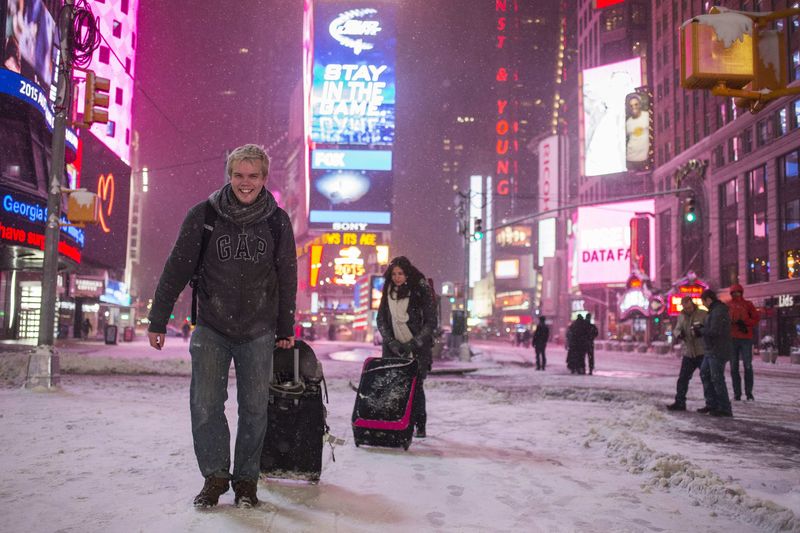 © Reuters. Turistas carregam bagagem na Times Square, sob neve, em Nova York