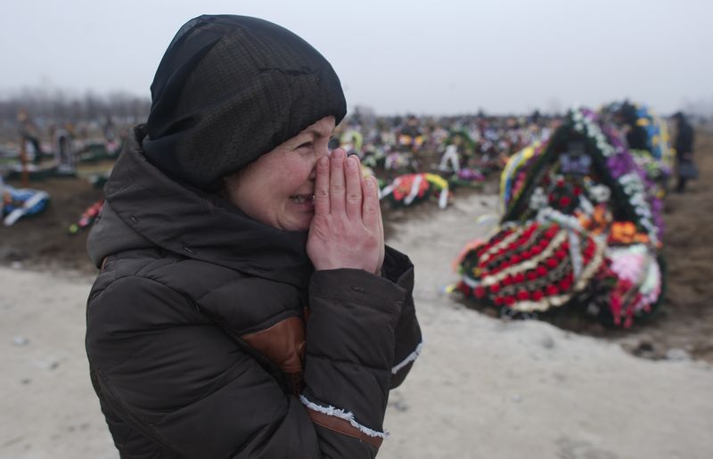 © Reuters. Familiar de vítima de bombardeio em cemitério de Mariupol