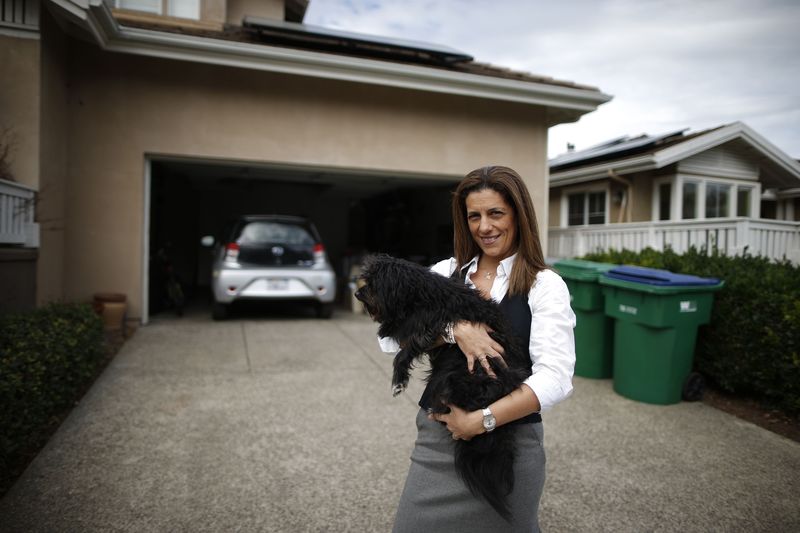 © Reuters. A computer science professor stands next to her home and her electric car in Irvine, California