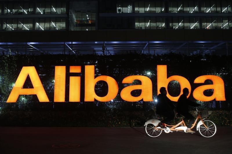 © Reuters. File photo of people riding a double bicycle past a logo of The Alibaba Group at the company's headquarters on the outskirts of Hangzhou