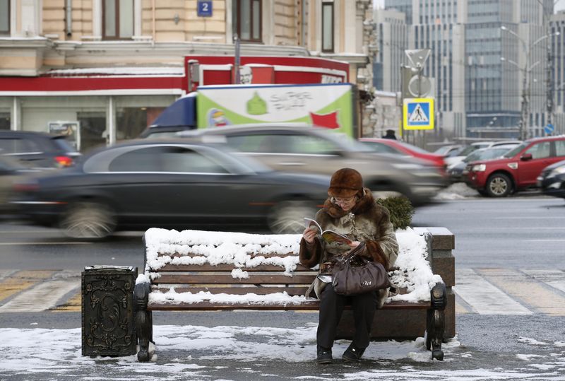 © Reuters. Woman sits on a bench and reads a magazine on a street in central Moscow