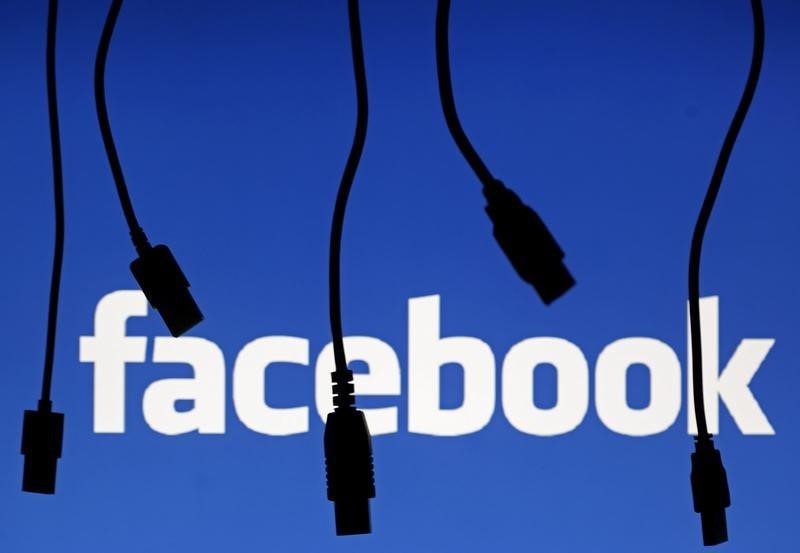 © Reuters. Electronic cables are silhouetted next to the logo of Facebook in this illustration photo in Sarajevo