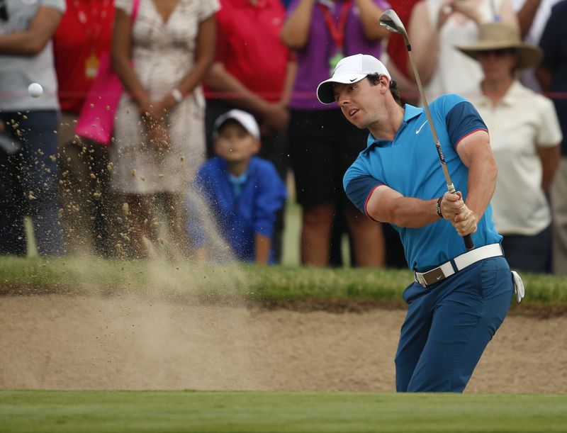 © Reuters. McIlroy of Northern Ireland hits the ball out off the bunker on the 18th hole during Abu Dhabi Golf championship