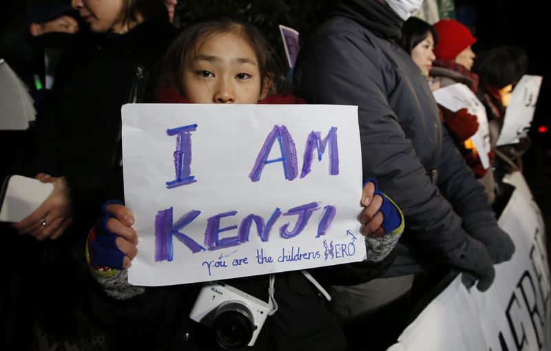 © Reuters. Girl holding a placard  chant "Save Kenji" during a vigil in front of the PM Abe's official residence in Tokyo