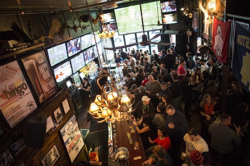 © Reuters. People watch the AFC championship football game between the Patriots and the Broncos at a bar in Hoboken