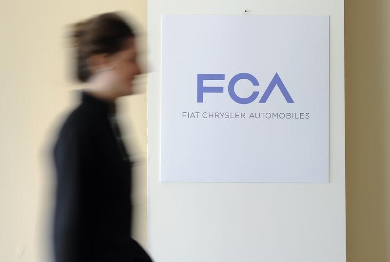 © Reuters. A woman walks past a logo of Fiat Chrysler Automobiles (FCA) in Turin