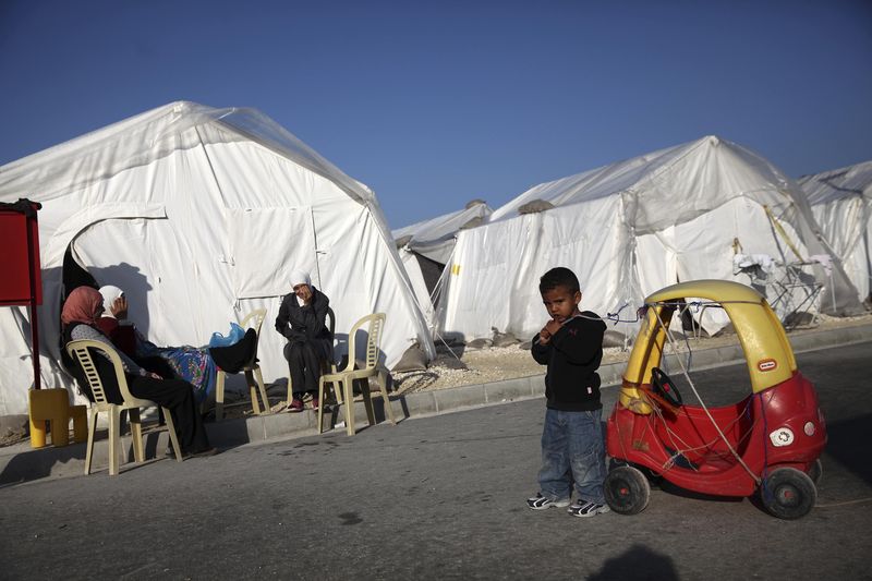 © Reuters. Syrian refugees sit outside the tents in Kokkinotrimithia refugee camp