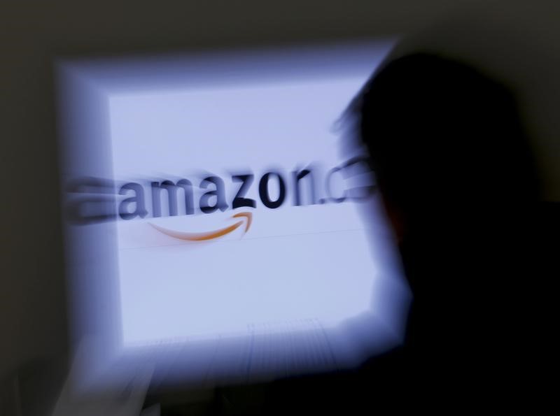 © Reuters. A zoomed illustration image of a man looking at a computer monitor showing the logo of Amazon is seen in Vienna