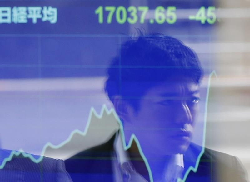 © Reuters. A passer-by is reflected on an electronic board showing Japan's Nikkei stock average at a brokerage in Tokyo