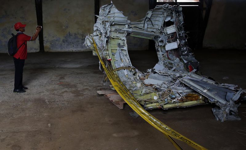 © Reuters. Man shoots video footage of part of the fuselage of crashed AirAsia Flight QZ8501 inside a storage facility at Kumai port in Pangkalan Bun