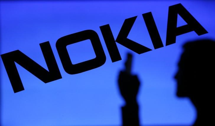 © Reuters. Мужчина с телефоном на фоне логотипа Nokia