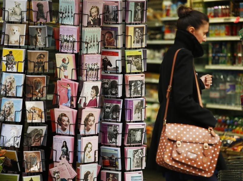 © Reuters. A woman passes racks of greetings cards displayed in a shop in London