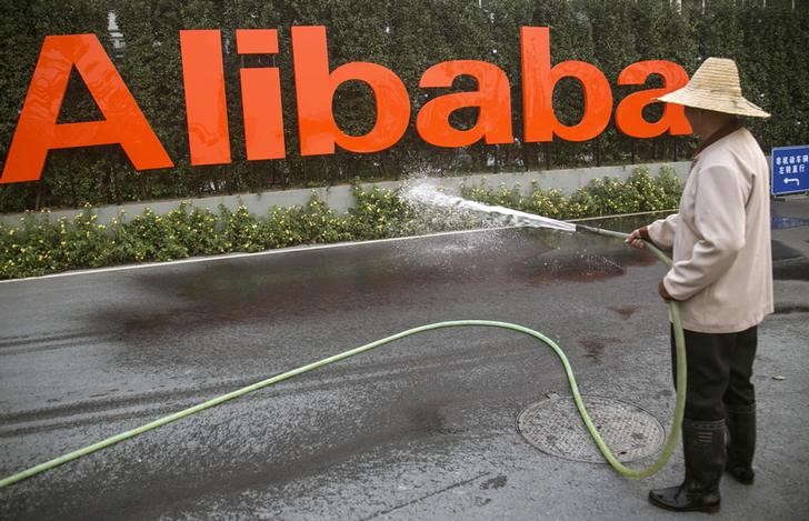 © Reuters. A cleaner waters the flowers below a logo of Alibaba (China) Technology Co. Ltd at the company's headquarters on the outskirts of Hangzhou