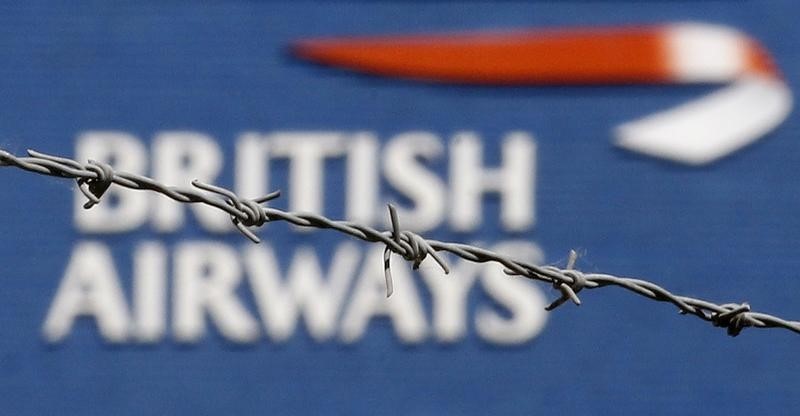 © Reuters. The British Airways logo is seen behind barbed wire at Heathrow Airport, west of London