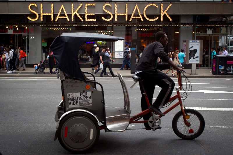 © Reuters. A pedicab rides past a Shake Shack restaurant in New York