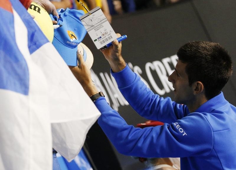 © Reuters. Novak Djokovic of Serbia signs autographs after defeating Milos Raonic of Canada in their men's singles quarter-final match at the Australian Open 2015 tennis tournament in Melbourne 