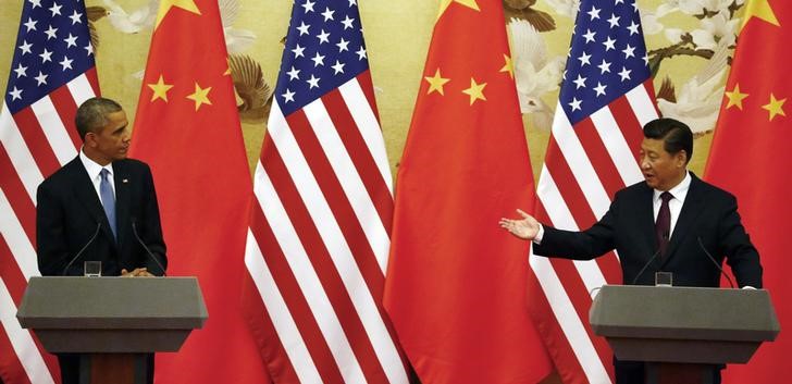 © Reuters. China's President Xi gestures as he and U.S. President Obama look at each other in front of U.S. and Chinese national flags during a joint news conference at the Great Hall of the People in Beijing