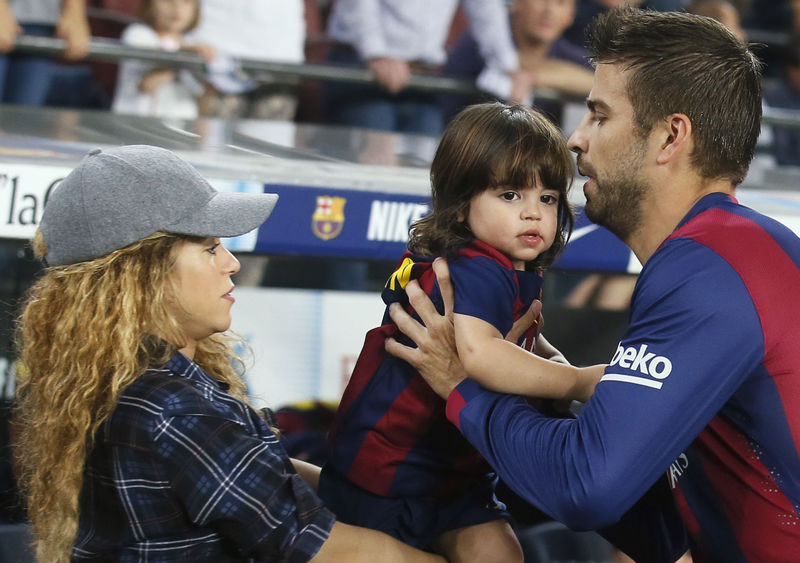 © Reuters. Singer Shakira passes their son Milan to Barcelona's Pique before the Spanish first division soccer match between Barcelona and Eibar at Camp Nou stadium in Barcelona