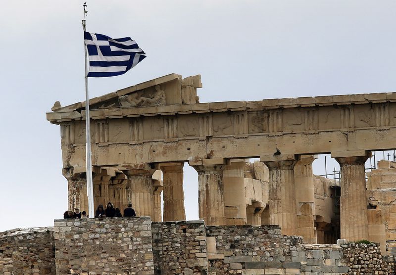 © Reuters. Tourists stand near the temple of Parthenon atop the ancient site of the Athens Acropolis on a cold and windy day
