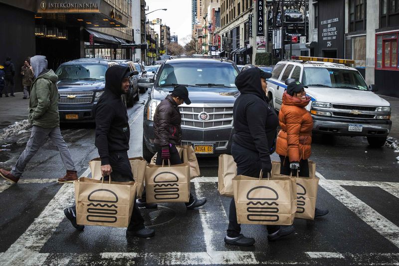 © Reuters. Employees carry delivery bags full of food out of a Shake Shack store in New York