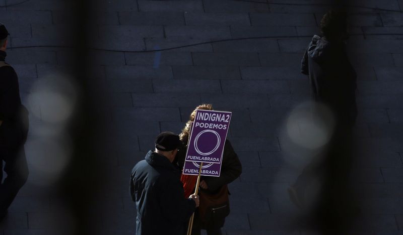 © Reuters. A man holds a placard in support of Spain's party "Podemos" (We Can) as he gathers, before the start of a rally called by Podemos, at Madrid's landmark Puerta del Sol