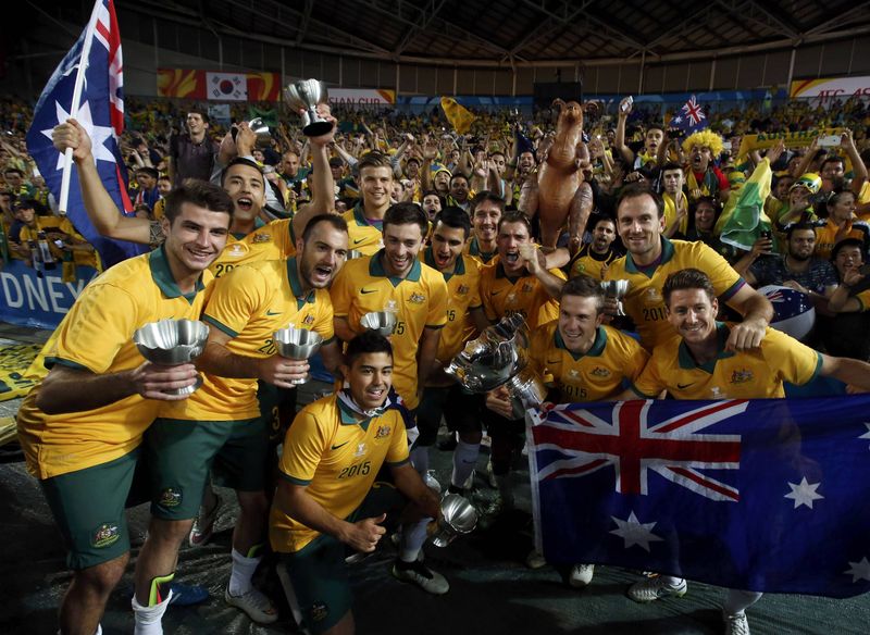 © Reuters. Australia's players pose for pictures with their medals and the Asian Cup trophy after they beat South Korea to win the tournament at the Stadium Australia in Sydney