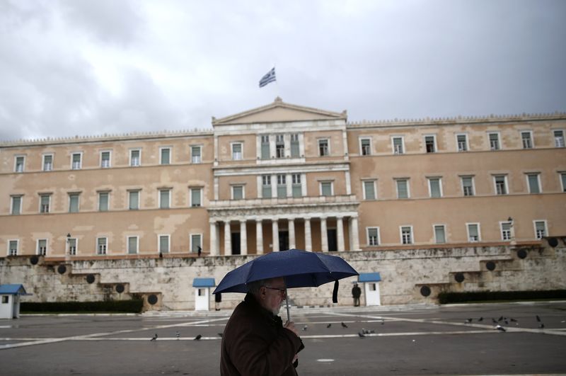 © Reuters. A man holding an umbrella makes his way in front of the Greek parliament during rainfall in Athens
