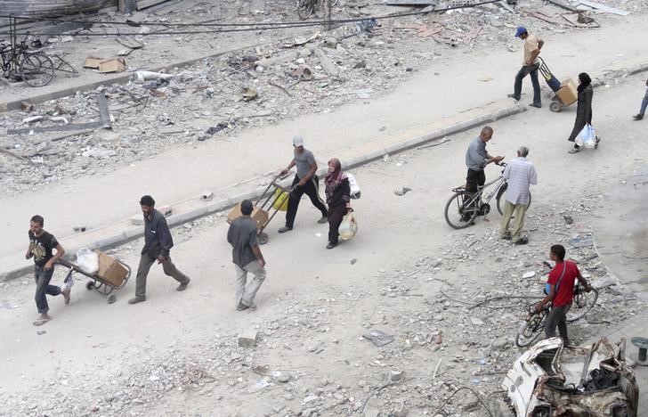 © Reuters. Residents walk as they receive aid at the Palestinian refugee camp in Yarmouk, south of Damascus