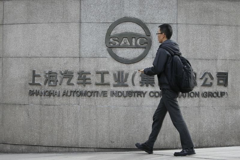 © Reuters. A man walks in front of the gate of Shanghai Automotive Industry Corp., in Shanghai