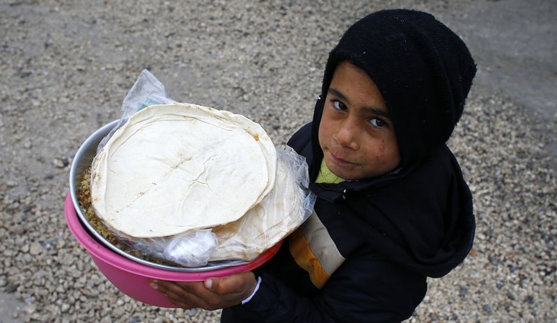 © Reuters. A Kurdish refugee boy from the Syrian town of Kobani carries food for his family during lunch time at a refugee camp in the border town of Suruc