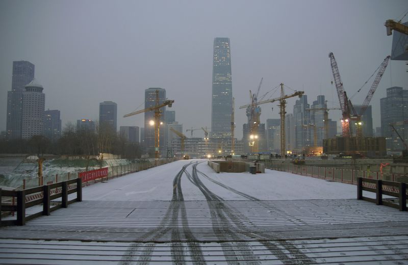 © Reuters. Tyre tracks are seen on a street covered by thin snow at a construction site at the central business district in Beijing