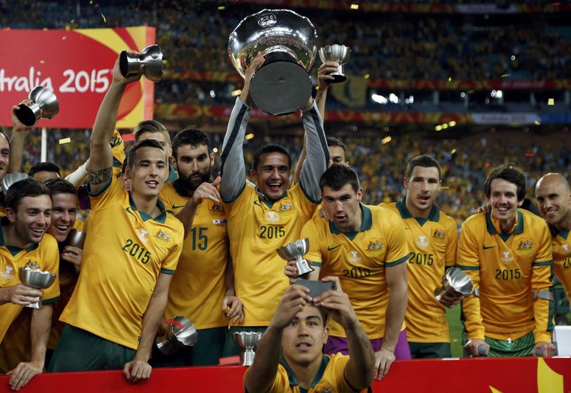 © Reuters. Australia's Massimo Luongo takes a selfie with his teammates celebrating behind him with their trophies and the Asian Cup after they beat South Korea to win the tournament at the Stadium Australia in Sydney