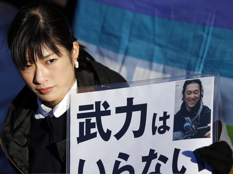 © Reuters. Woman holds a portrait of Japanese journalist Kenji Goto on a placard during a rally against Japan's Prime Minister Shinzo Abe in front of Abe's official residence in Tokyo