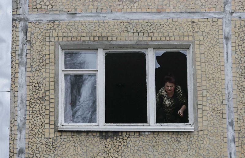 © Reuters. A woman looks out of the window of a residential block damaged by a shelling in Donetsk, eastern Ukraine