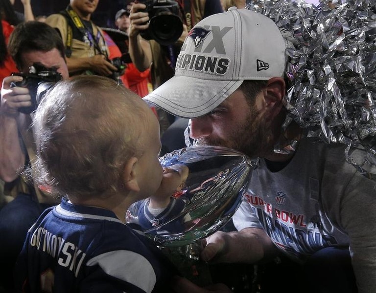 © Reuters. New England Patriots kicker Stephen Gostkowski kisses the Vince Lombardi Trophy with his youngest son after defeating the Seattle Seahawks in the NFL Super Bowl XLIX football game in Glendale
